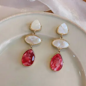 Detailed view of elegant marbled resin drop earrings featuring red and white waterdrop pendants