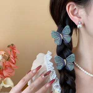 Detailed view of green embroidered butterfly hair clips on a braided hairstyle.