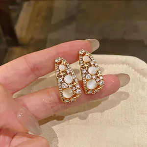 Dettaglio di orecchini vintage a stella dorati con pietre bianche sulle dita