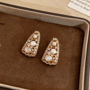 Primo piano di orecchini vintage in oro con trafori a stella in zircone e pietre.