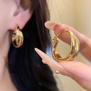 Primer plano de aretes de aro chapados en oro de 18 quilates con acabado brillante.