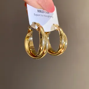 Primer plano de pendientes de doble aro chapados en oro de 18 quilates con brillo.