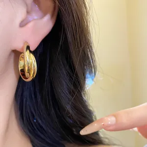 Primer plano de elegantes pendientes de aro doble chapados en oro 18K para un look de lujo