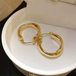 Primer plano de aretes de aro chapados en oro de 18 quilates con diseño trenzado