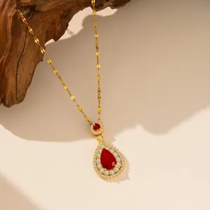 Dettaglio di collana con zircone rosso a goccia con catena dorata e accenti bianchi.