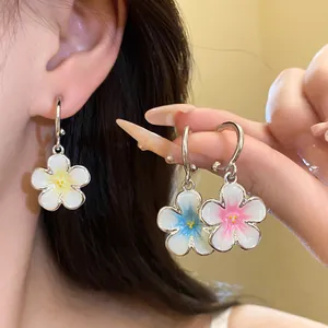 Dettaglio di orecchini a sospensione con fiori in smalto colorato e ganci a C.
