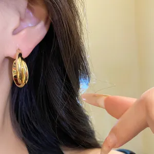 Primer plano de pendientes de aro gruesos minimalistas bañados en oro de 18K para mujer