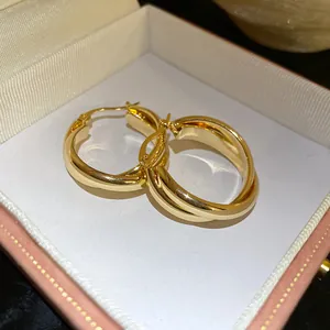 Primer plano de pendientes de aro entrelazados bañados en oro de 18K en estilo vintage