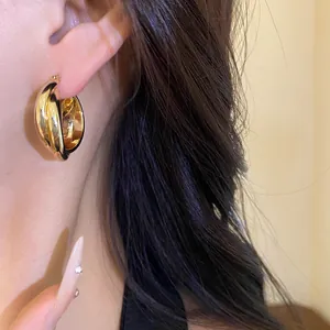 Primer plano detallado de elegantes pendientes de aro de doble capa chapados en oro 18K