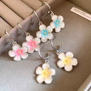 Primo piano di orecchini a cerchio a C con eleganti pendenti a fiori smaltati.