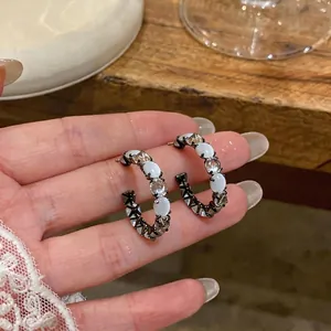 Elegant C-shaped hoop earrings featuring white cat's eye stones and sparkling clear zircons