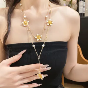 Detailed view of gold Y-shaped necklace with enamel flower pendants and faux pearls