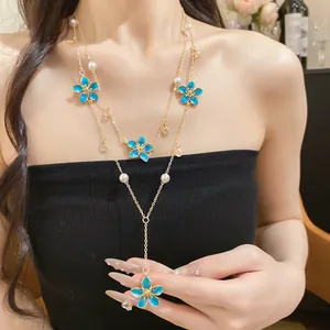 Close-up of double-layered Y-shaped necklace with blue enamel flowers and pearls.