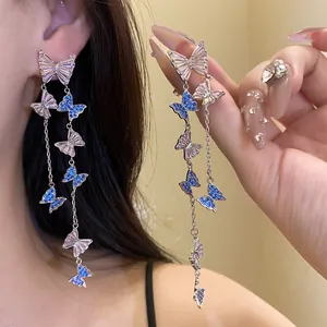 Close-up of elegant silver needle earrings featuring shimmering blue and clear zircons.