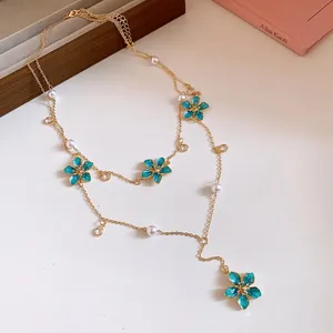 Detailed view of layered Y-shape necklace with turquoise enamel flowers and faux pearls