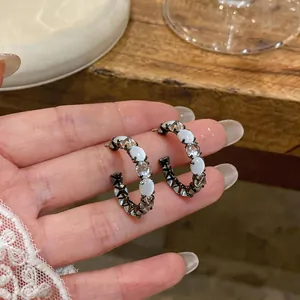 Detailed macro view of Korean style C-hoop earrings with cat's eye and zircon stones