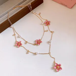 Detailed view of sweet pink enamel flower Y-necklace with pearls and gold chain.