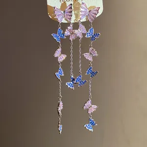 Detailed view of zircon butterfly tassel earrings with pink and blue stones.