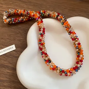 Detailed macro view of a colorful hand-woven rainbow bead necklace on a white ceramic tray.