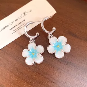 Dettaglio di orecchini a C con pendenti a fiore in smalto blu sfumato in argento