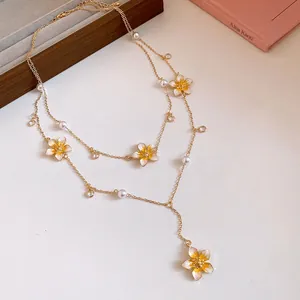 Detailed view of the layered Y-shaped gold necklace with yellow enamel flowers.