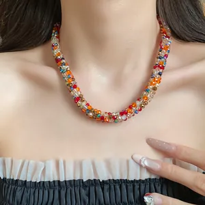Close-up of a vibrant hand-woven rainbow bead necklace on a model's neckline.