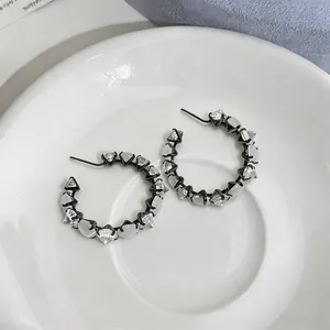 Close-up of black hoop earrings with alternating clear zircons and white cat's eye stones