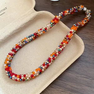 Macro view of a handcrafted colorful rainbow beaded braided necklace in a jewelry tray.