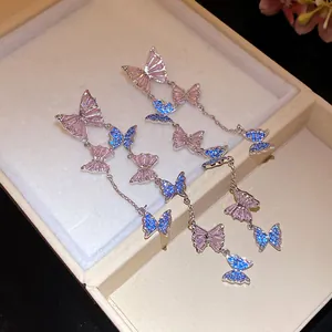 Detailed view of elegant silver needle tassel earrings with sparkling pink and blue butterflies