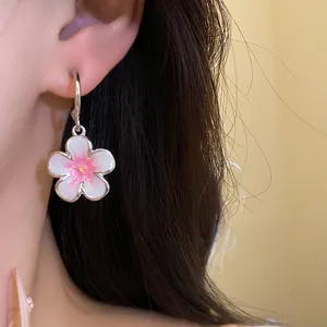 Primo piano di orecchini pendenti a fiore con centro rosa smaltato e ago in argento