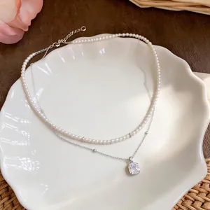 Elegante collar de doble capa con perlas pequeñas y colgante de cristal cuadrado.