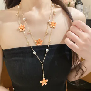 Detailed shot of layered gold necklace with orange drip oil flowers and pearls