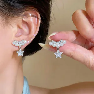 Détail en gros plan d'élégants clips d'oreilles en or avec étoiles, perles et zircons brillants