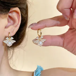 Detailed macro view of gold-plated bow earrings with pearls and micro-paved zirconia