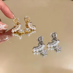Gros plan de boucles d'oreilles clips étoile et perle sur surface réfléchissante