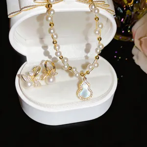Close-up of pearl necklace with gourd pendant and matching bowknot earrings in a box
