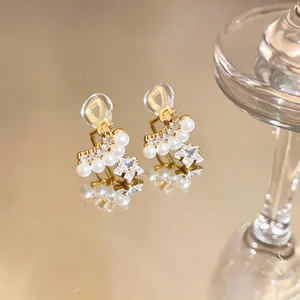 Gros plan d'élégantes boucles d'oreilles à clip étoile et perle plaquées or sur miroir