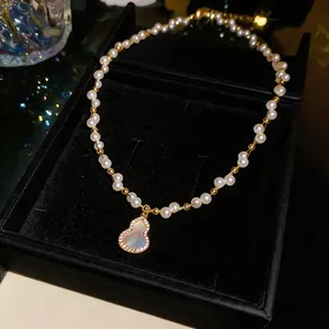 Detail view of 18k gold plated gourd pendant necklace with pearls in a black box.