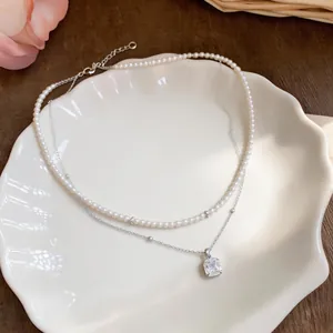 Primer plano de collar de perlas de doble capa con colgante de cristal cuadrado