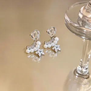 Vue détaillée de boucles d'oreilles clips étoile en or 14 carats avec zircons et perles.