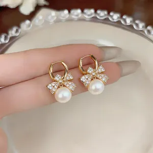 Detailed view of 18k gold plated bow-knot earrings with shimmering zircon and pearls