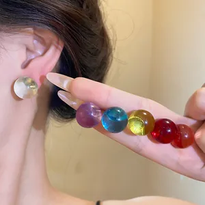 Close-up view of colorful round resin stud earrings with silver needles on model