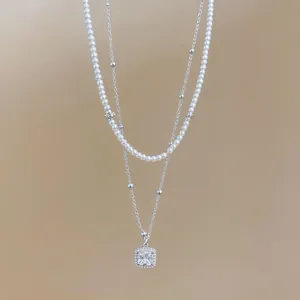Primer plano de un collar de doble capa con perlas y colgante de cristal cuadrado
