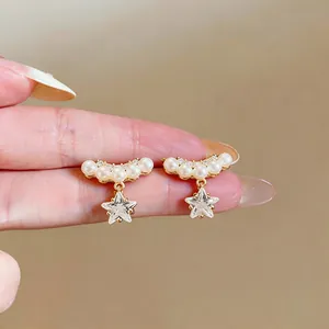 Détail rapproché des clips d'oreilles étoile en or 14k avec zircon et perles fines