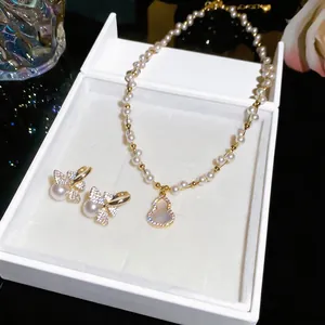Close-up of 18k gold plated pearl necklace with gourd pendant and butterfly earrings in box.