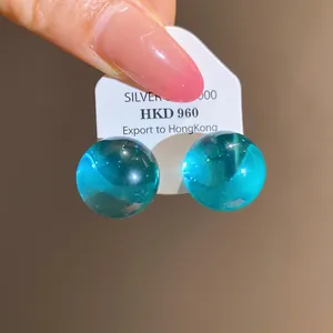 Macro detail of minimalist turquoise round resin stud earrings with silver pins