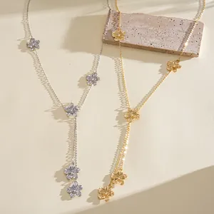 Detail view of gold and silver floral tassel necklaces on a textured stone background