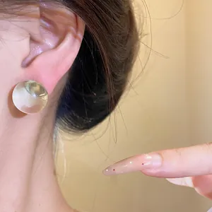Close-up detail of a minimalist round translucent resin earring with a silver needle.