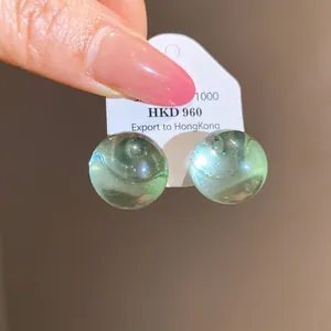 Detailed view of light green translucent resin bead stud earrings on a display card