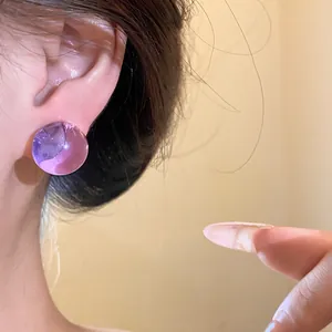 Detailed view of a person wearing a stylish purple translucent round resin stud earring